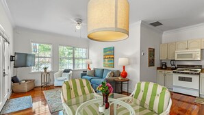 A spacious living room with a large window, a television, and a kitchen area with a microwave and stove.