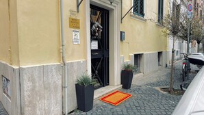 L’entrée d’un hôtel, avec une porte noire, une enseigne jaune et un paillasson rouge et jaune.
