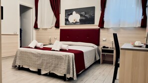 A neatly arranged hotel room with a bed, bedside table, and a desk. - Hotel Balilla (Rome)