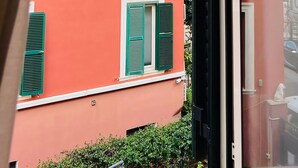 Une vue à travers la fenêtre d’un bâtiment doté d’un balcon et d’une porte.