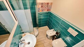 Ein Badezimmer mit Dusche, zwei Toiletten, einem Waschbecken und einem Spiegel.