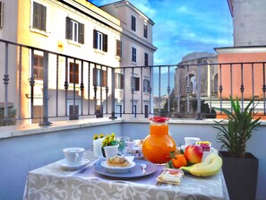 A balcony with a table set for breakfast, including a pitcher of orange juice, fruits, and pastries. - Hotel Balilla (Rome)