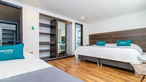 A hotel room with two beds, a wardrobe, a mirror, and a small table. - Hotel Bogota Alpes Polo Club (Bogotá)
