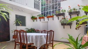 A dining area with a table and chairs, surrounded by potted plants and hanging flower baskets. - Hotel Bogota Alpes Polo Club (Bogotá)