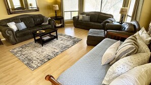 A spacious living room with a large bed, two sofas, a coffee table, and a ceiling fan. - CRC331*Direct Comal River Access*Walk to Downtown NBTX (New Braunfels)