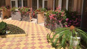 A courtyard with tiled flooring, potted plants, and a palm tree. - Hotel Beatris (Nessebar)