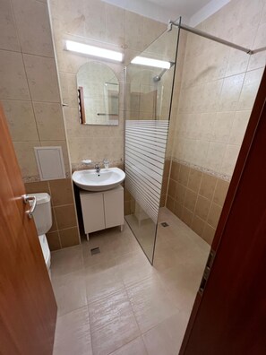 A bathroom with a glass shower enclosure, a sink, and a toilet.