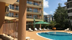 A swimming pool area with lounge chairs and a palm tree. - Hotel Beatris (Nessebar)