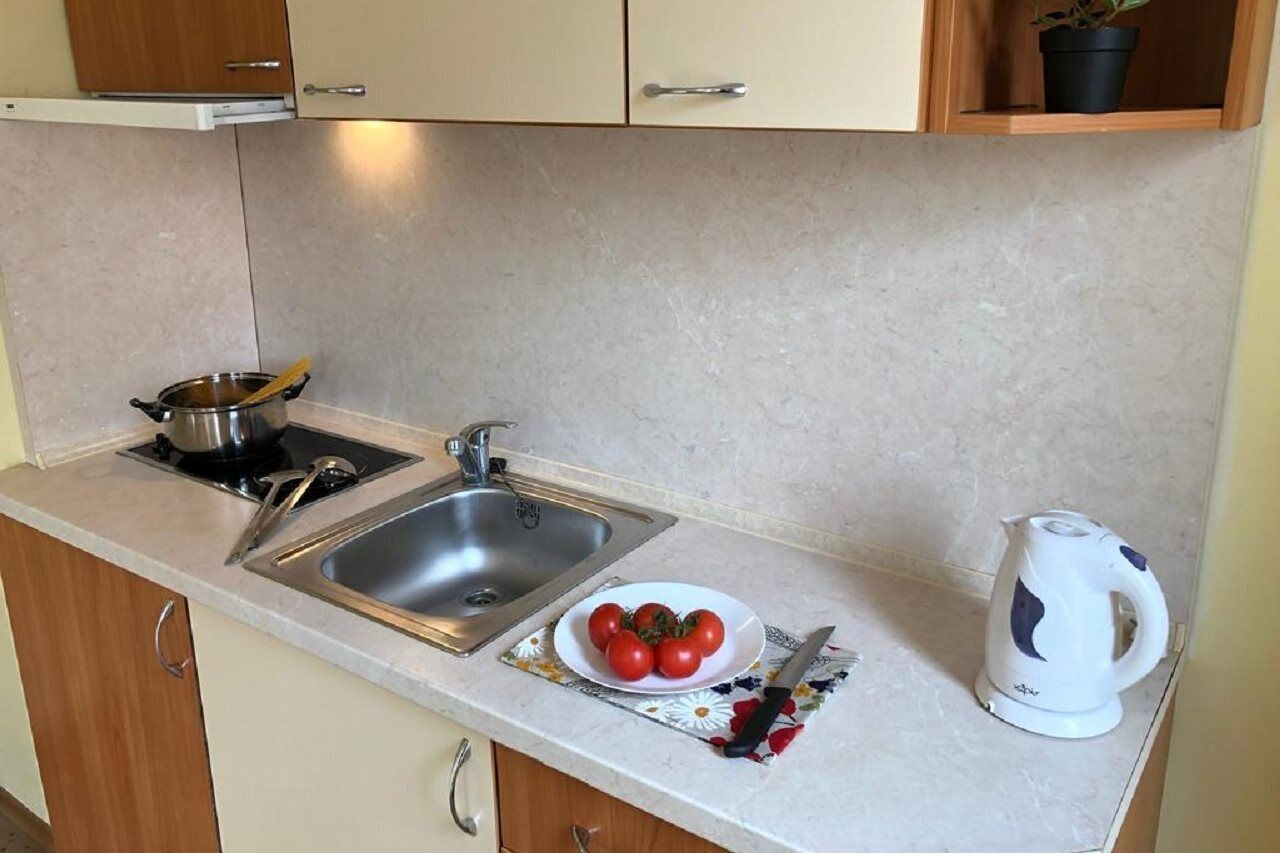A small kitchenette with a sink, stove, and a kettle.