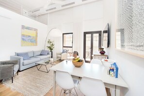 A modern living room with a sofa, coffee table, and dining area.