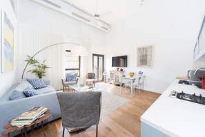 Ein modernes Wohnzimmer mit einer Couch, einem Sessel und einem Essbereich mit Tisch und Stühlen.