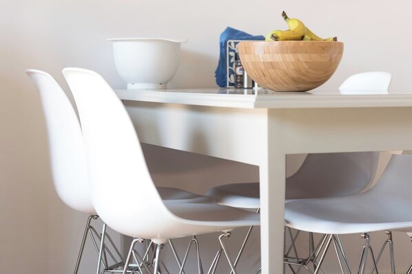 A dining table with a wooden bowl containing bananas, a white bowl, and a blue napkin.