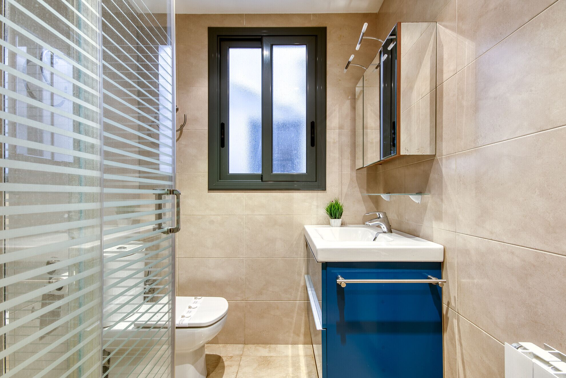 Un baño moderno con inodoro, lavabo y ventana.