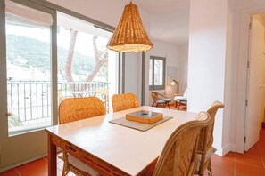 A dining area with a table, chairs, and a hanging light fixture.