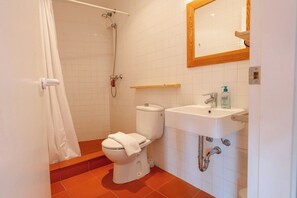 A bathroom with a toilet, shower, sink, and mirror.