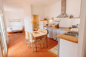 A compact kitchen with a dining area, white walls, and a tiled floor.
