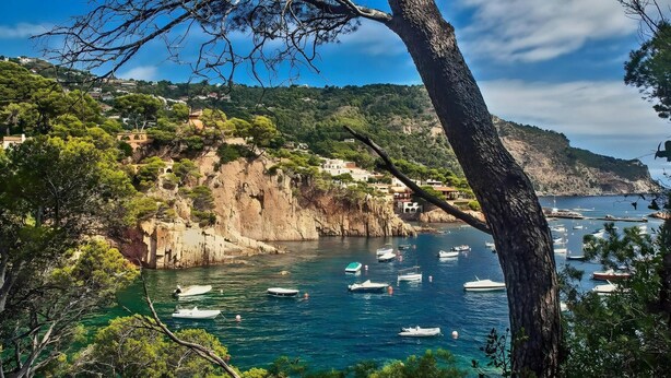 Un paysage côtier caractérisé par des falaises rocheuses, des eaux d’un bleu limpide et la présence de bateaux.