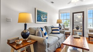 A living room with a sofa, two lamps, a painting, and a wooden coffee table. - Cypress at Jubilee Suites Bed & Breakfast. 1K/1Q/1B (Fairhope)