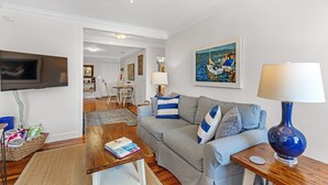 A living room with a sofa, a coffee table, a TV, and a painting. - Cypress at Jubilee Suites Bed & Breakfast. 1K/1Q/1B (Fairhope)
