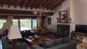 Un salón amplio con una araña, sofás, un televisor y una chimenea.