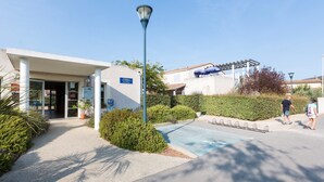 Entrada de un hotel con un corredor cubierto, una farola y una zona de estacionamiento.