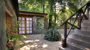 A stone staircase leading to a wooden door with a glass panel, surrounded by lush greenery and a stone wall. - Posada del Sauce (Villa General Belgrano)