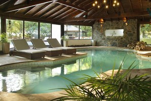 A pool area with lounge chairs, a stone wall, and a view of the outdoors. - Posada del Sauce (Villa General Belgrano)
