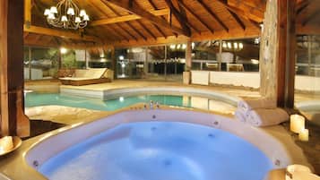 Un jacuzzi con velas, una piscina y un área de descanso con vistas a la piscina.