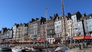 Una zona sul lungomare con edifici storici, un porto turistico con imbarcazioni e una passeggiata pedonale.
