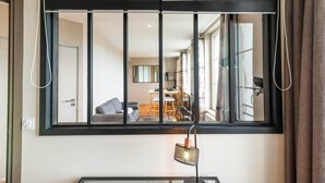 Una stanza con un'ampia finestra, una scrivania con lampada e vista su un'area ristorazione.