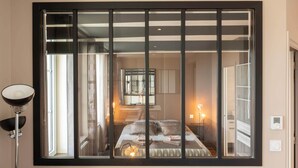 Una camera da letto con un'ampia finestra, una lampada da comodino e un letto con cuscini.