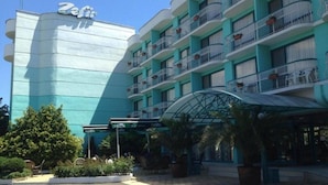 Un hotel con una entrada curva, varios balcones y un letrero que dice 'Zefie'.