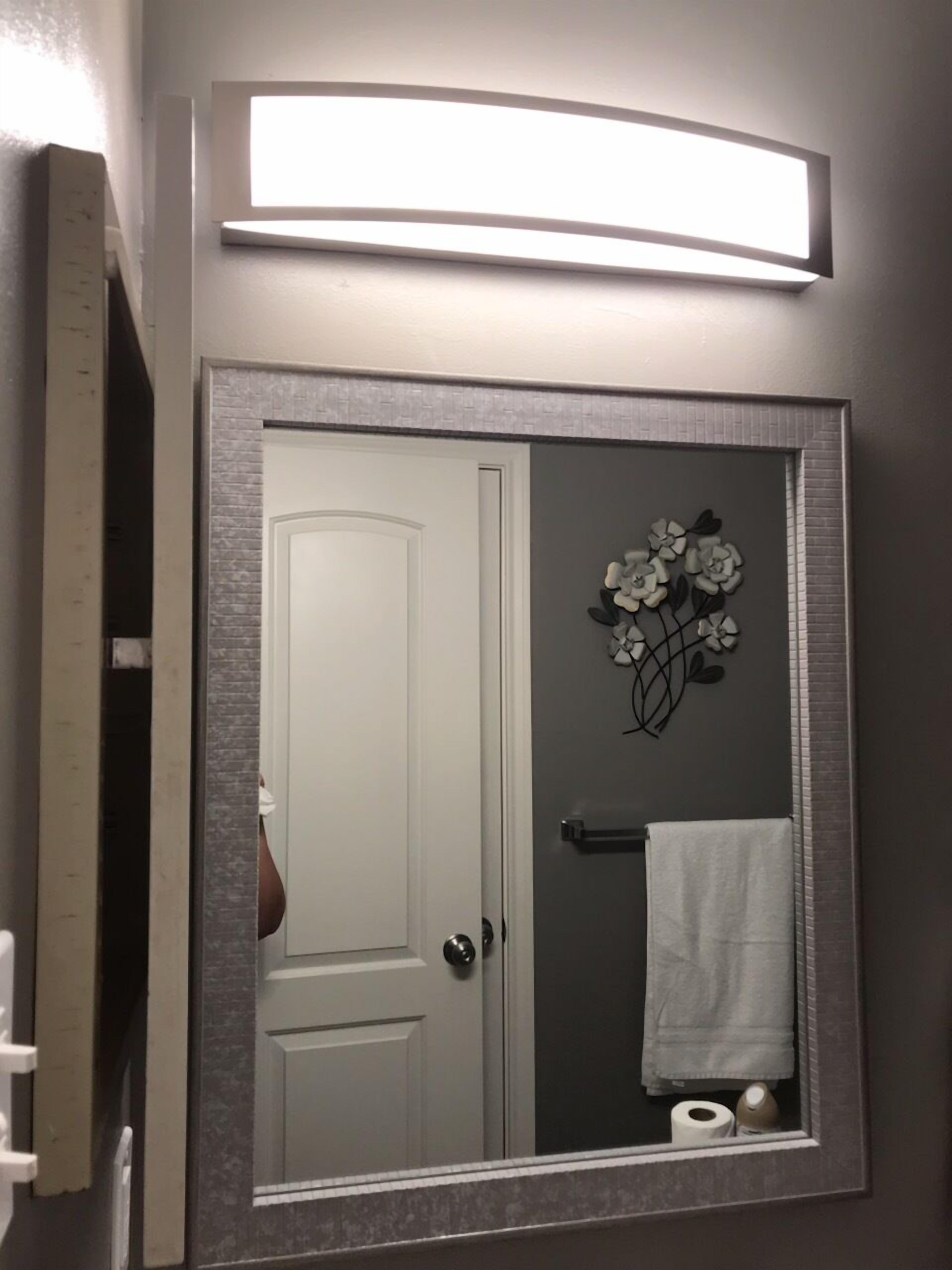A bathroom with a mirror, a towel rack, and a toilet paper holder.