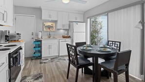 A modern kitchen with white cabinets, a built-in oven, and a dining area with a round table and chairs.