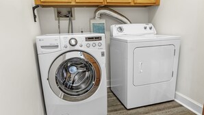 Un cuarto de lavandería con lavadora de carga frontal y secadora de carga superior.