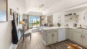 Una cocina moderna con una isla central, armarios blancos y vistas al exterior.
