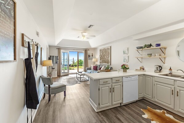 Una cocina moderna con una isla central, armarios blancos y vistas al exterior.