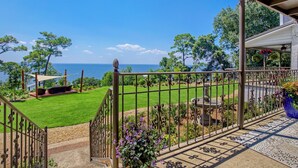 A balcony with a view of the sea, a grassy lawn, and a pergola. - Magnolia at Jubilee Suites Bed & Breakfast. 1K/1B. (Fairhope)