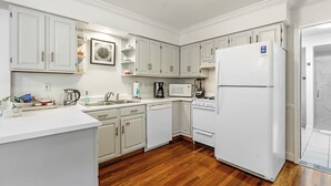 A kitchen with white cabinets, a refrigerator, a microwave, a coffee maker, and a dishwasher. - Magnolia at Jubilee Suites Bed & Breakfast. 1K/1B. (Fairhope)