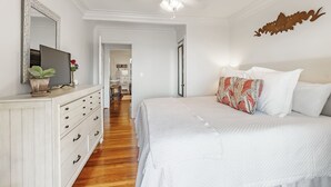 A bedroom with a bed, dresser, mirror, and a ceiling fan. - Magnolia at Jubilee Suites Bed & Breakfast. 1K/1B. (Fairhope)