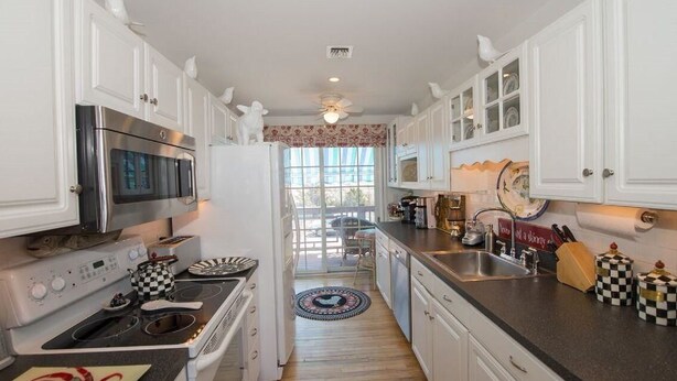 A kitchen with white cabinets, a stainless steel oven, and a black countertop. - Beautiful Waterfront Colonial (Wading River)