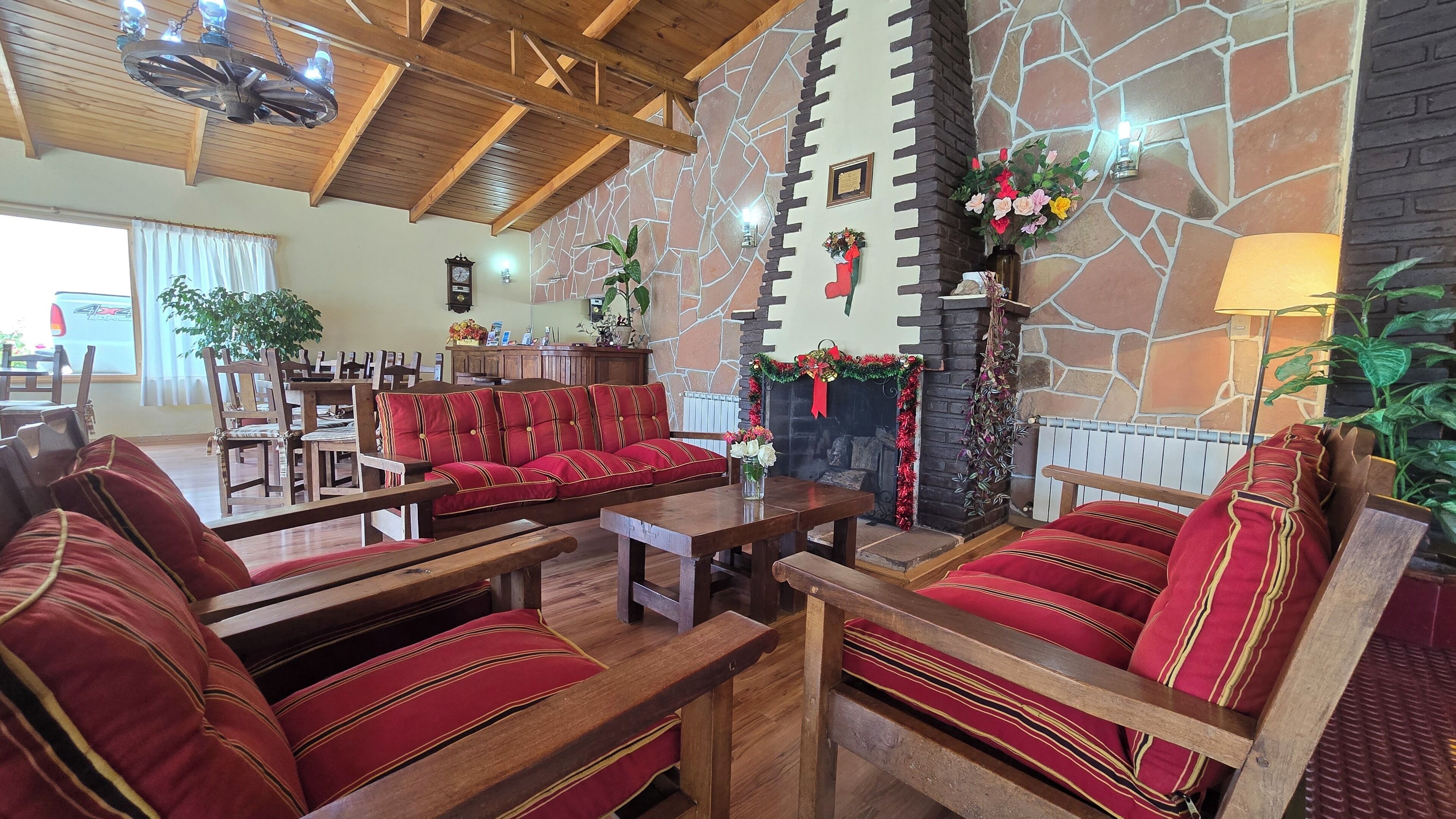 Una hall accogliente con arredi in legno, una parete in pietra e un camino decorato con ghirlande festive.