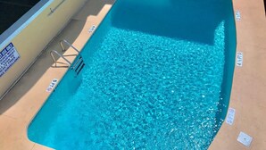 A swimming pool with clear blue water, a ladder, and a sign indicating a 4-foot depth.