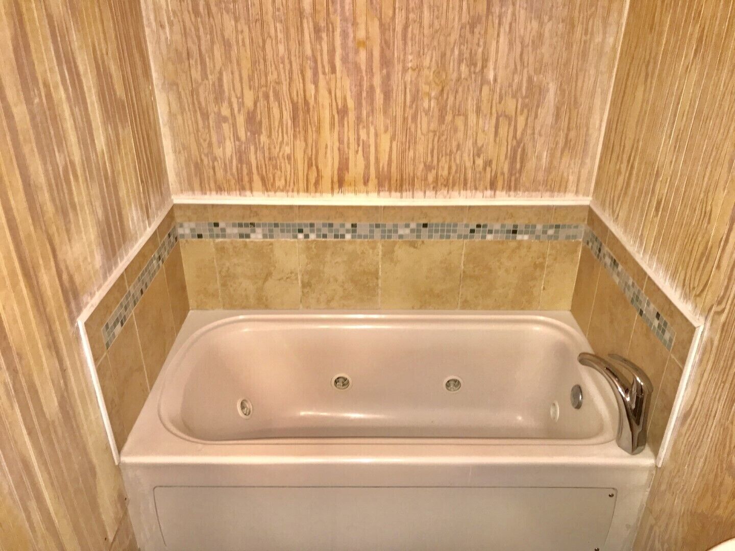 A bathroom with a bathtub, tiled walls, and a wooden panel design.
