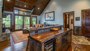 A spacious kitchen with a wooden ceiling, large windows, and a stone fireplace. - Prancing Horse at Eagles Nest - hot tub, great view, resort amenities, summer concerts! (Banner Elk)