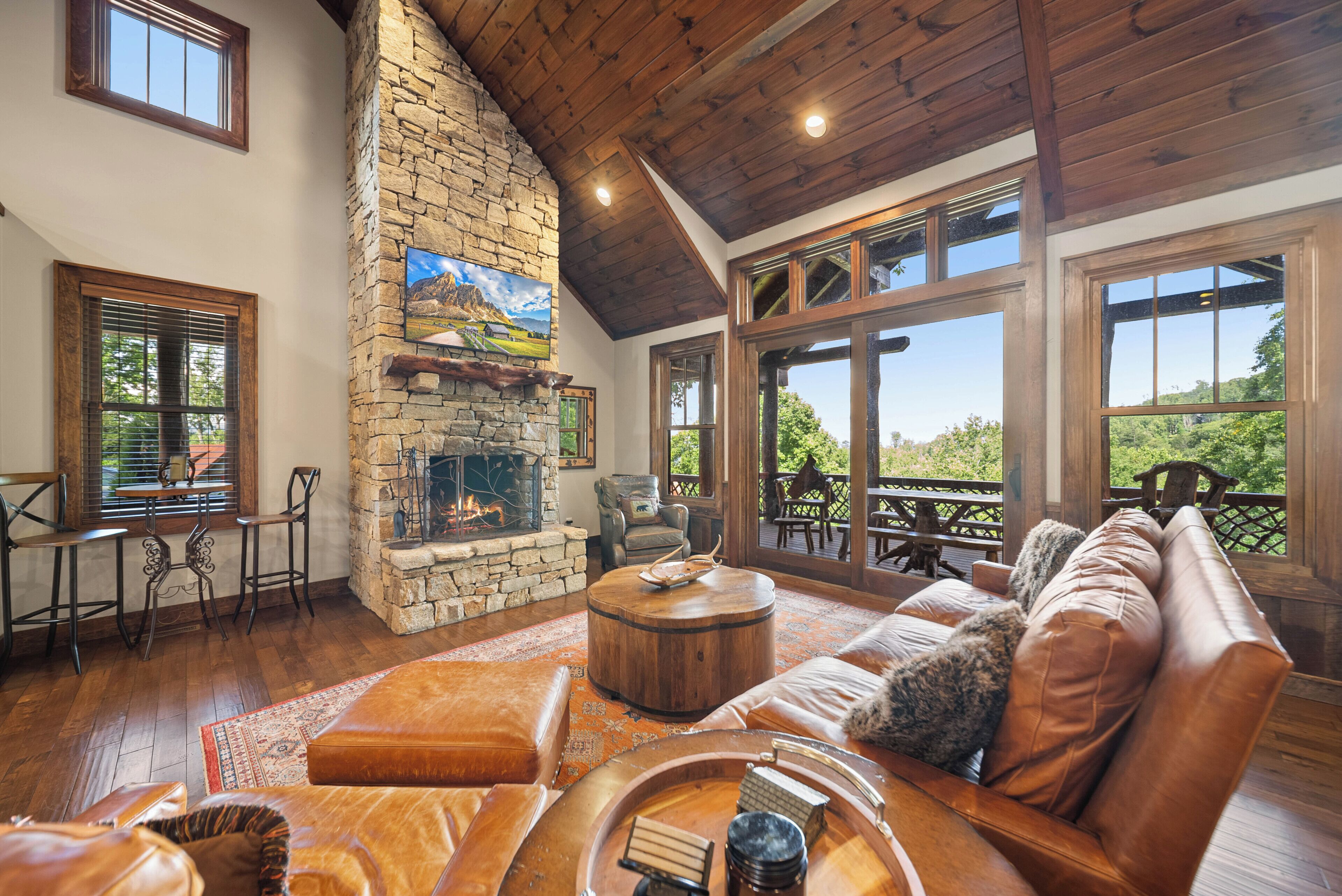 Un amplio salón con chimenea de piedra, asientos de cuero y ventanas grandes que ofrecen vistas al exterior.