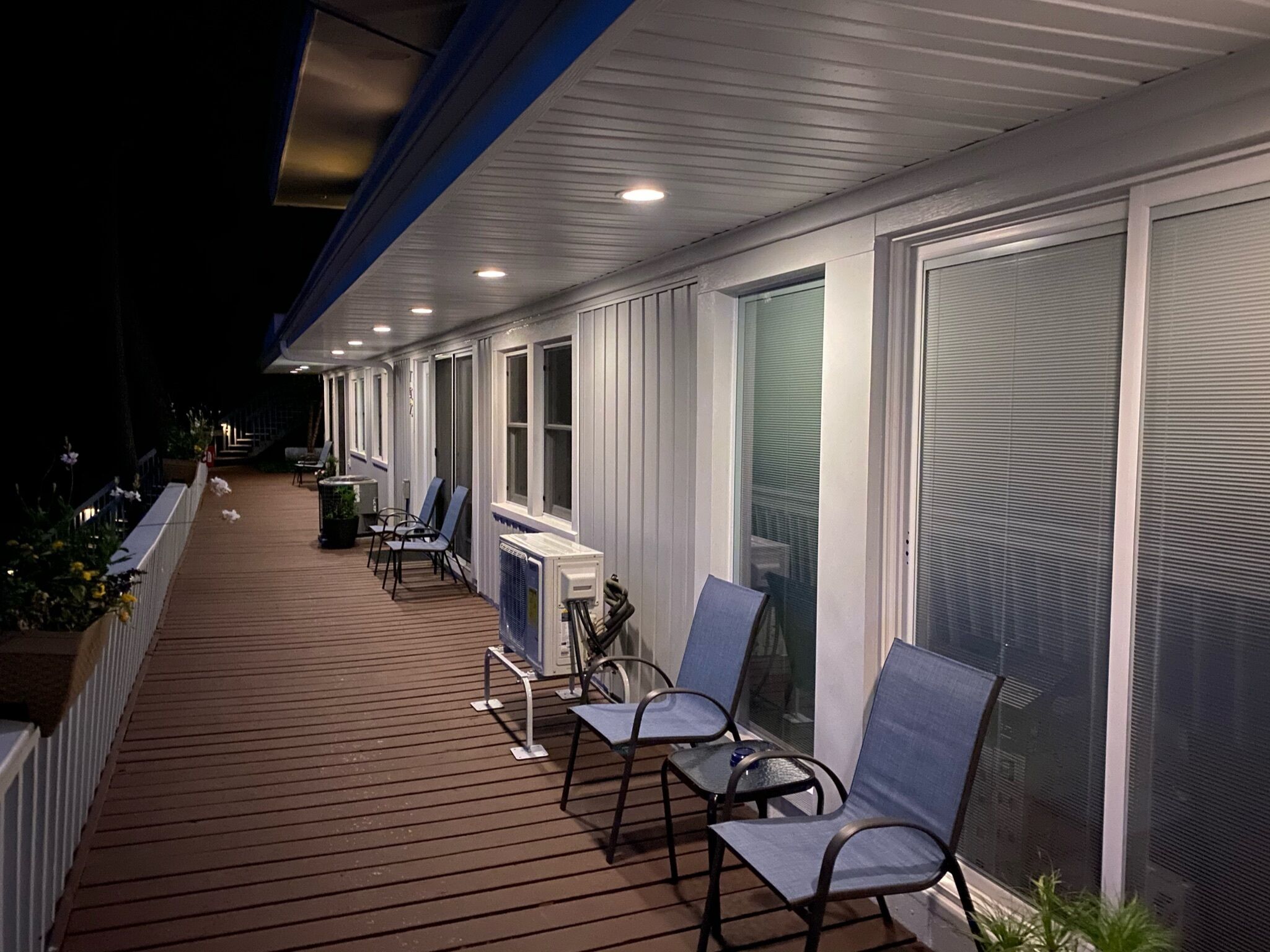 Une terrasse extérieure couverte, dotée de sièges et d’un ventilateur, et entourée de fenêtres.