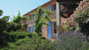 Un edificio rustico con tetto in tegole, un balcone e un giardino pieno di piante e fiori.