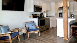 A modern kitchen with white cabinets, stainless steel appliances, and a wooden dining area. - The Overlook at Lake Hamilton - Contemporary Design, Private Deck & Boat Slip! (Hot Springs)