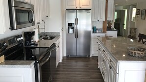 A modern kitchen with white cabinetry, stainless steel appliances, and a granite countertop. - The Overlook at Lake Hamilton - Contemporary Design, Private Deck & Boat Slip! (Hot Springs)